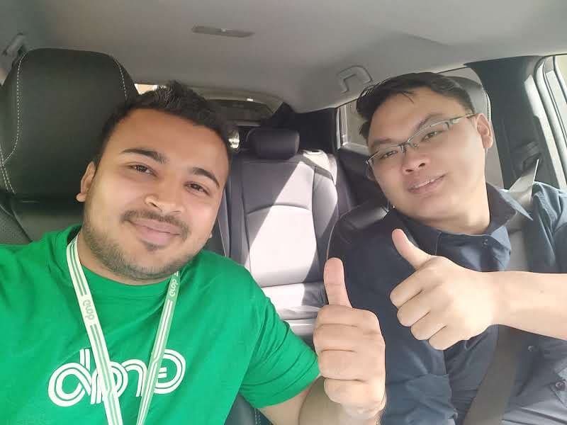 Two of us in a car, one in a green Grab t-shirt giving a thumbs up