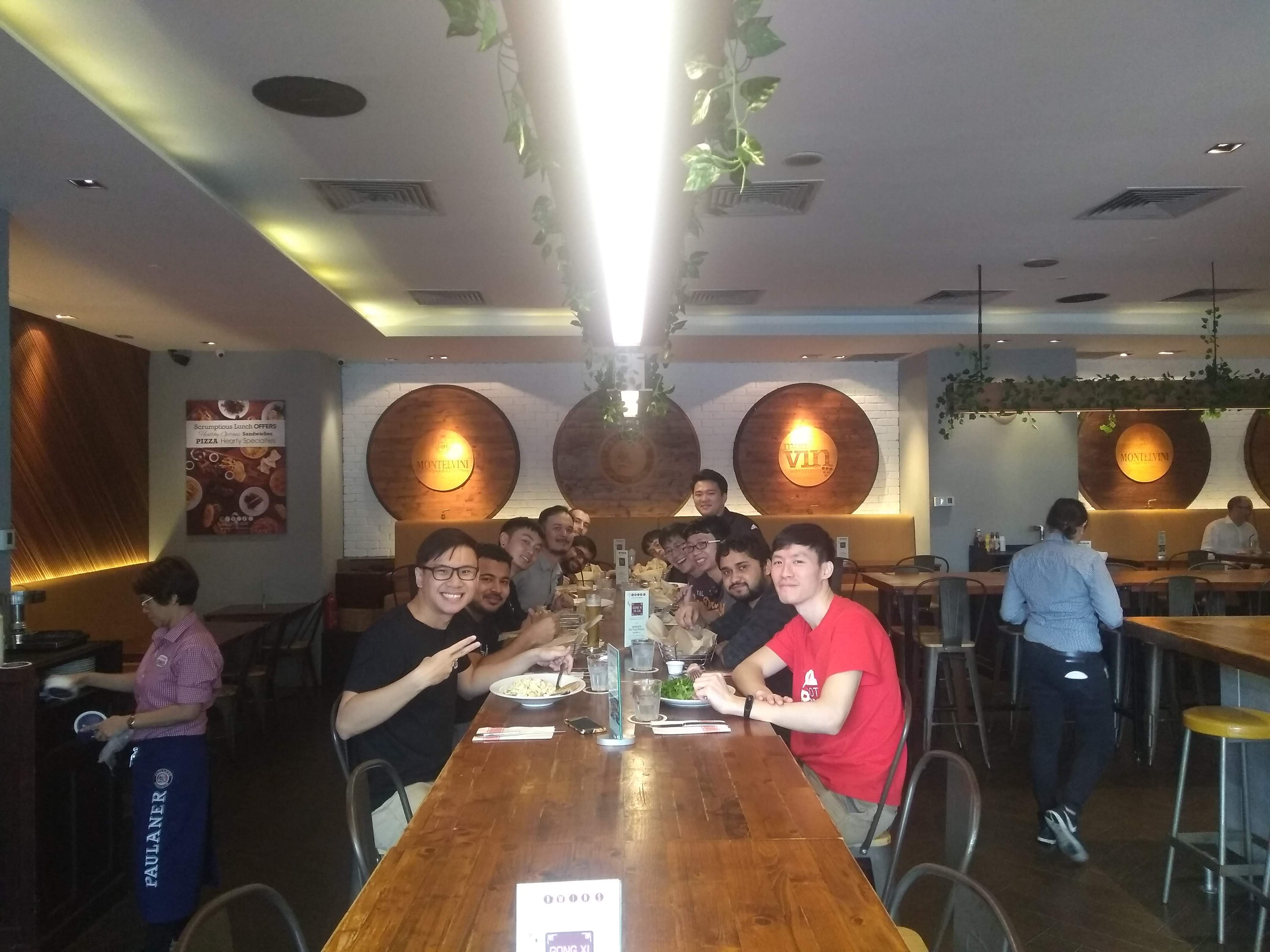A dozen of us leaning in for the camera around a long table over a team lunch